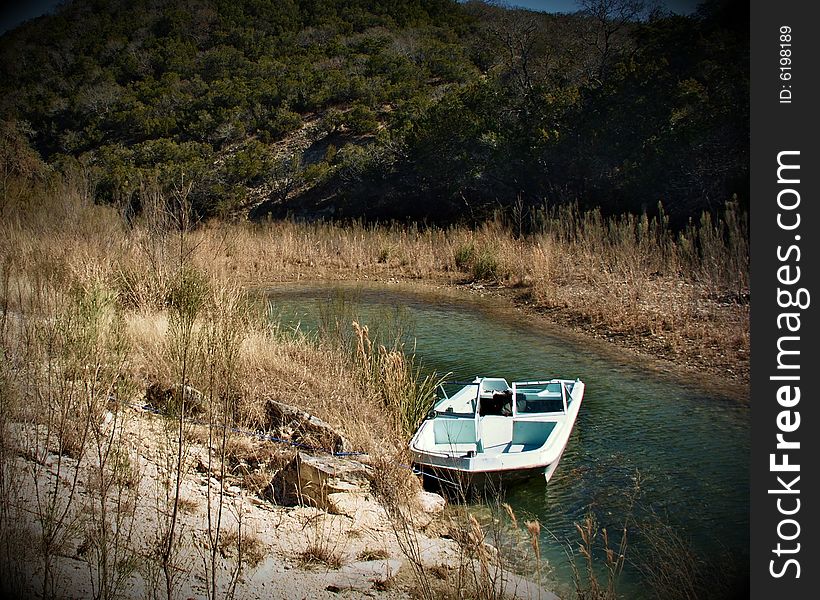 This small boat sits waiting a future passenger to explore this clear spring fed creek near Kerrville, Texas. This small boat sits waiting a future passenger to explore this clear spring fed creek near Kerrville, Texas