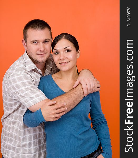 Casual couple together standing on orange background. Casual couple together standing on orange background