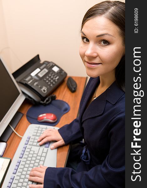 Attractive brunette woman sitting at desk in office. Attractive brunette woman sitting at desk in office