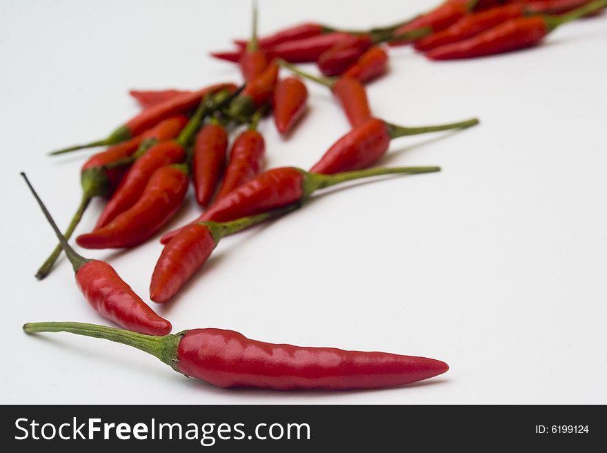 An arrangement of small red chili peppers isolated against a white background