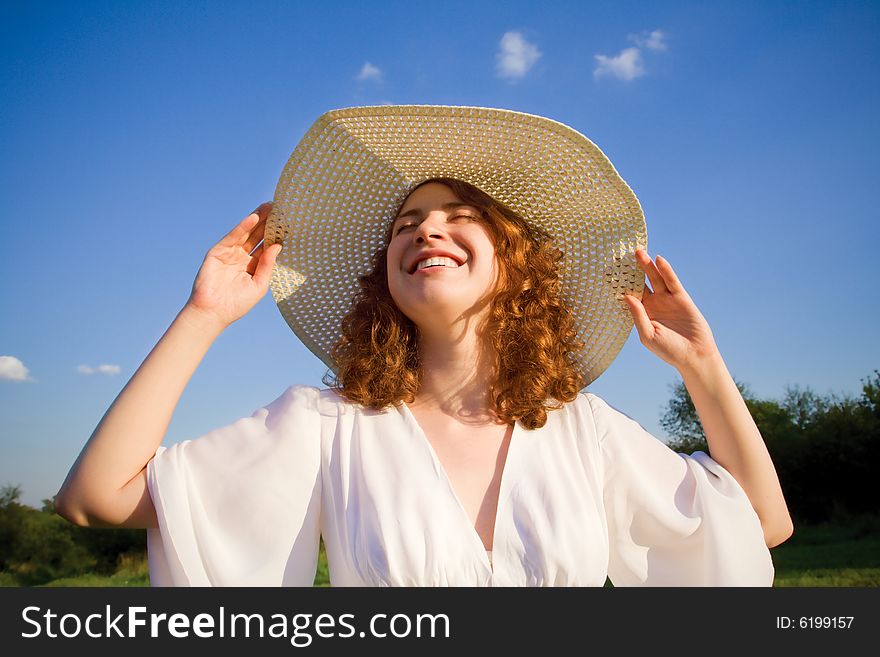 Smiling girl in white dress on the blue sky