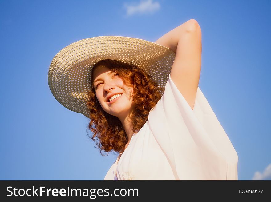 Smiling girl in white dress on the blue sky