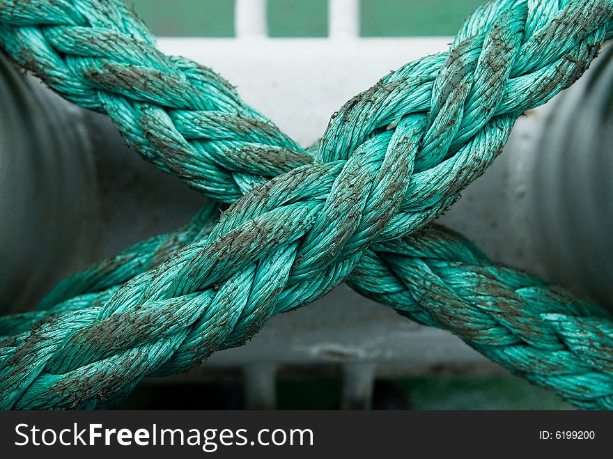 Green x-shaped rope over white mooring. Green x-shaped rope over white mooring