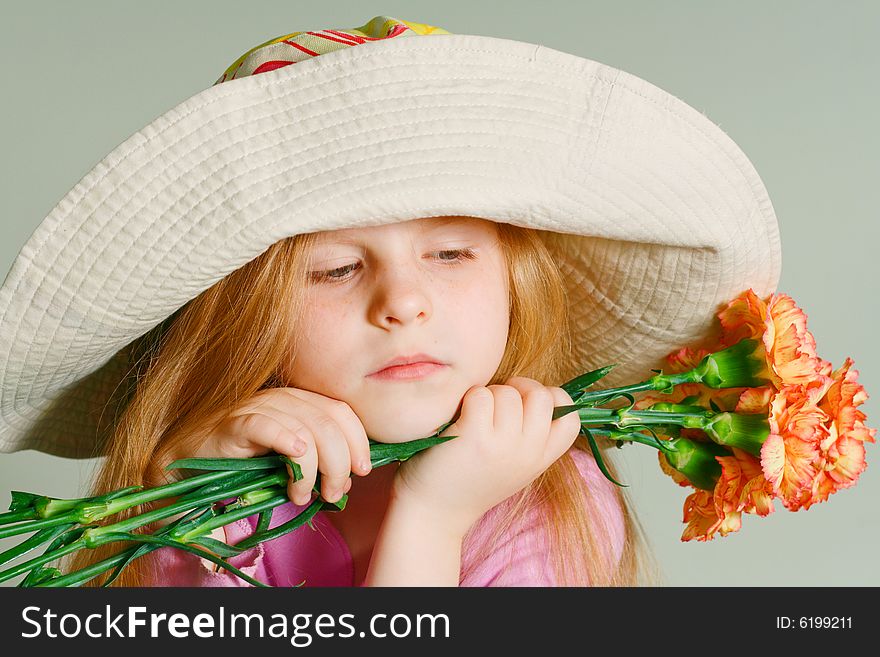 Small pensive girl in a big hat with pink flowers