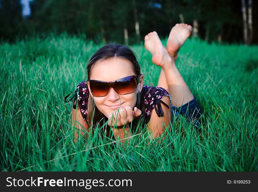 Young beautiful girl in sun glasses lying in green grass. Young beautiful girl in sun glasses lying in green grass