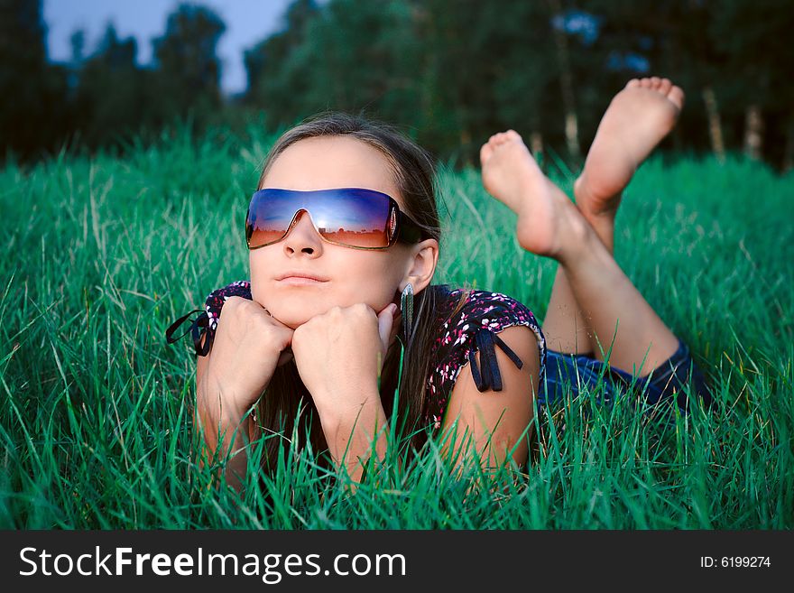 Young beautiful girl in sun glasses lying in green grass. Young beautiful girl in sun glasses lying in green grass