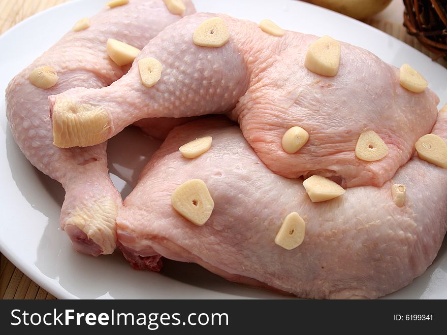 3 pieces of fresh and raw chicken with some garlic. 3 pieces of fresh and raw chicken with some garlic