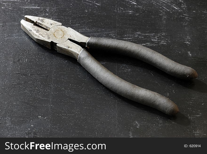 A pair of pliers on a black surface. A pair of pliers on a black surface