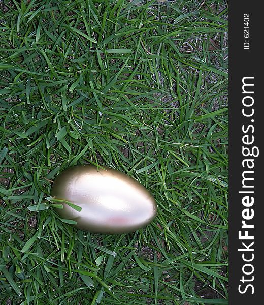 A golden egg laying in bright green rye grass.