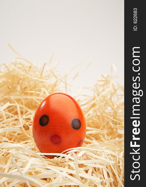 Coloured easter egg in wooden grass on grey background