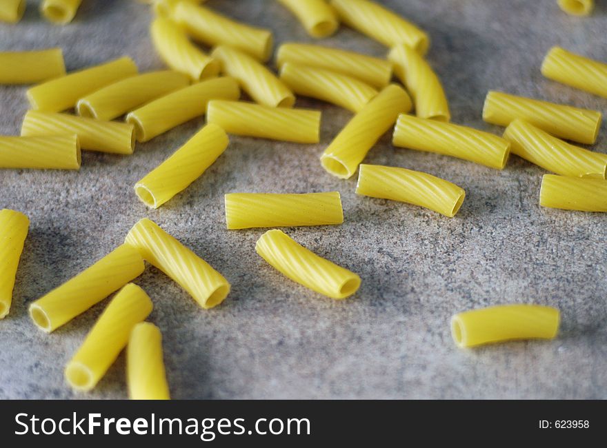 Scattered pieces of dried pasta on a tiled countertop. Scattered pieces of dried pasta on a tiled countertop