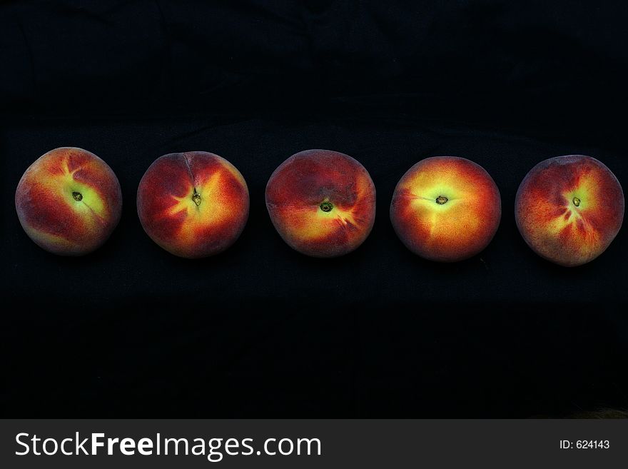 Five peaches against a black background