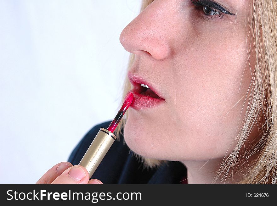 A woman applying lipstick. A woman applying lipstick.