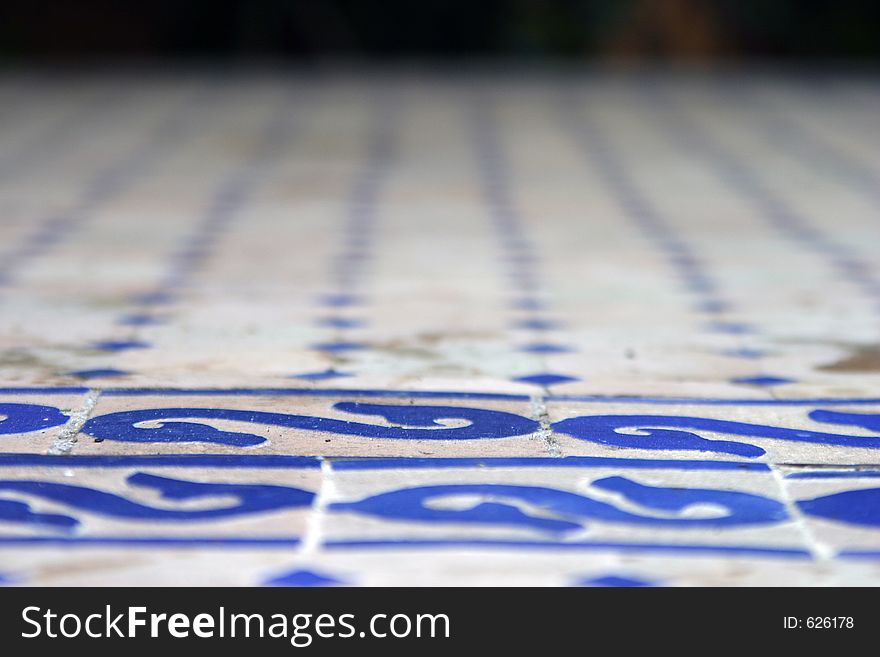 Detail of table top tiled with patterned blue and off-white handmade ceramic tiles. Detail of table top tiled with patterned blue and off-white handmade ceramic tiles.