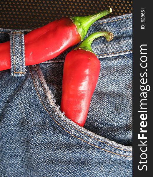 A pair of fashionable hot denim jeans. The red chilies are used as a concept to depict the denim is of the current fashion trend. A pair of fashionable hot denim jeans. The red chilies are used as a concept to depict the denim is of the current fashion trend.