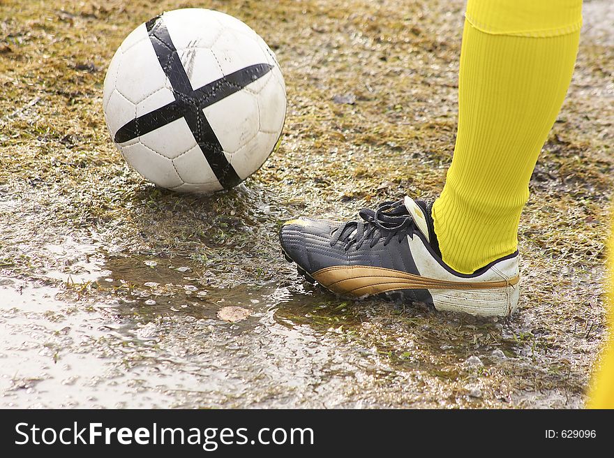 Players leg with ball on mudd. Players leg with ball on mudd