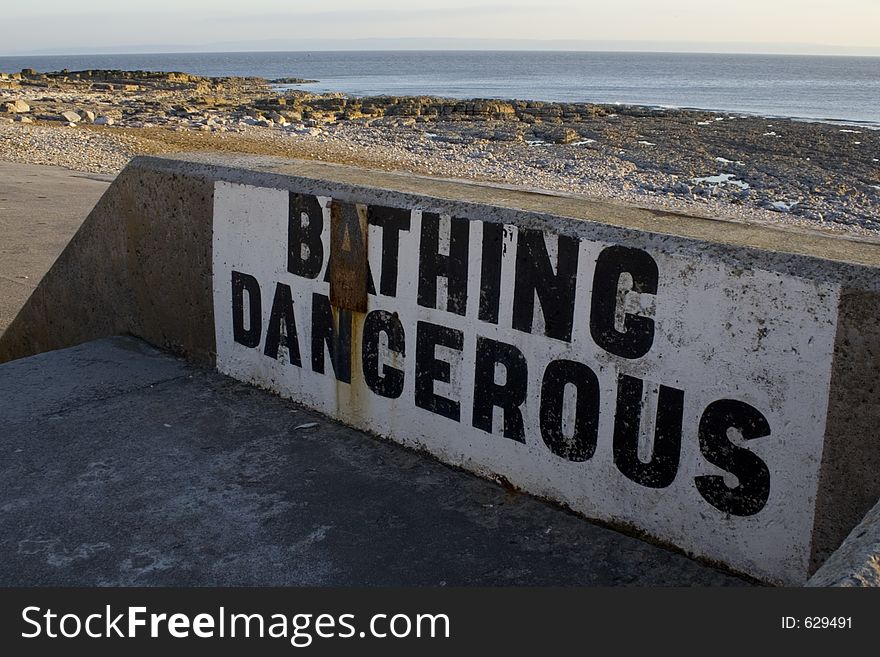 Weathered warning painted onto sea wall at Porthcawl, South Wales, UK. Weathered warning painted onto sea wall at Porthcawl, South Wales, UK