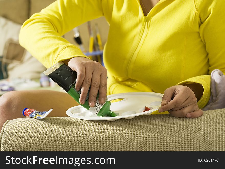 Painter applying green paint on her palette. Horizontally framed photo. Painter applying green paint on her palette. Horizontally framed photo.