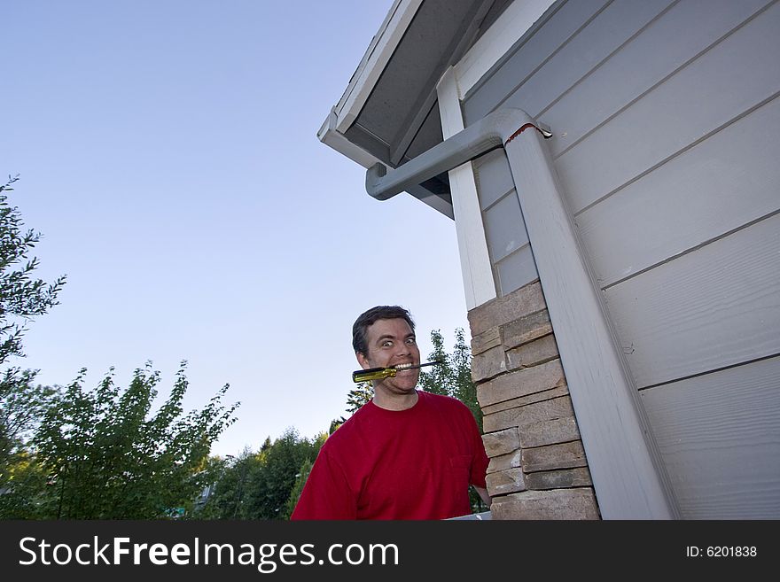 Man  with a screwdriver in his mouth and a smile on his face. Horizontally framed photo. Man  with a screwdriver in his mouth and a smile on his face. Horizontally framed photo