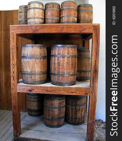 Two different sizes of wooden barrels on a wooden shelf.