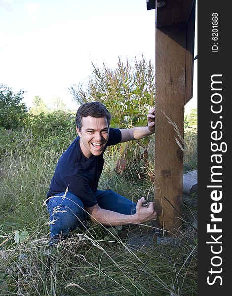 Man fixing a beam on a house with a wrench. Vertically framed photo. Man fixing a beam on a house with a wrench. Vertically framed photo.