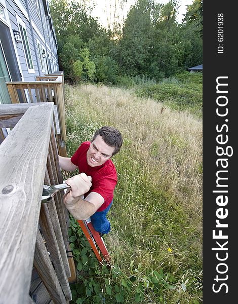 Man with a  grimace on his face standing on a ladder fixing a porch with a wrench. Vertically framed photo. Man with a  grimace on his face standing on a ladder fixing a porch with a wrench. Vertically framed photo.