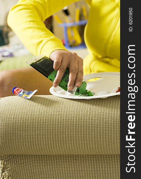 Painter applying green paint on her palette. Vertically framed photo. Painter applying green paint on her palette. Vertically framed photo.