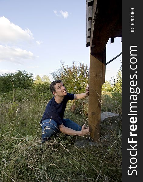 Man fixing a beam on a house with a wrench. Vertically framed photo. Man fixing a beam on a house with a wrench. Vertically framed photo.