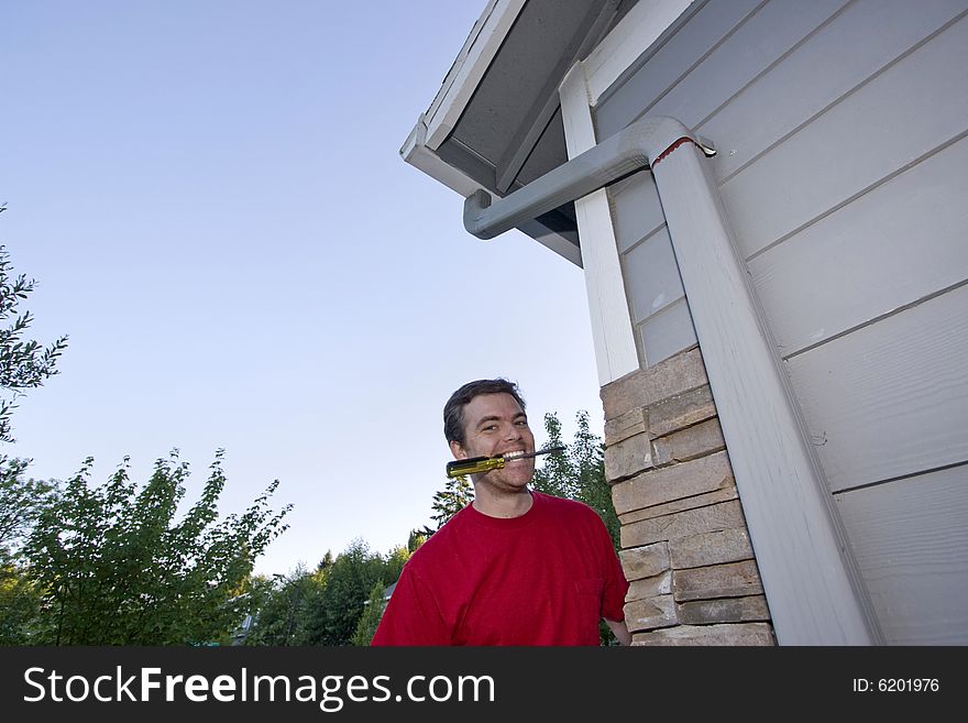 Man  with a screwdriver in his mouth and a smile on his face. Horizontally framed photo. Man  with a screwdriver in his mouth and a smile on his face. Horizontally framed photo