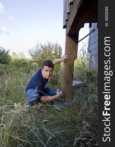 Man fixing a beam on a house with a wrench. Vertically framed photo. Man fixing a beam on a house with a wrench. Vertically framed photo.