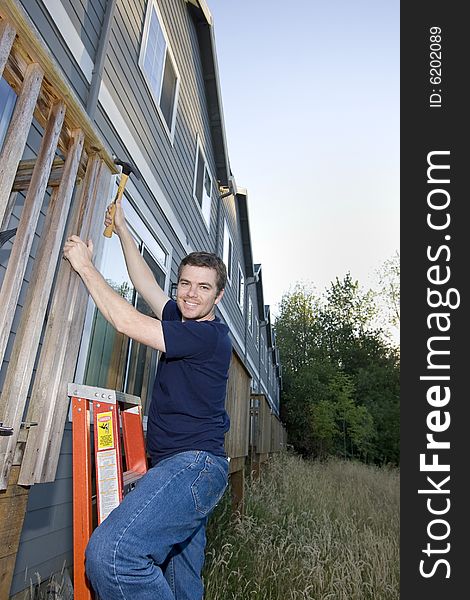 Smiling man using a hammer to fix a house. Vertically framed photo. Smiling man using a hammer to fix a house. Vertically framed photo.