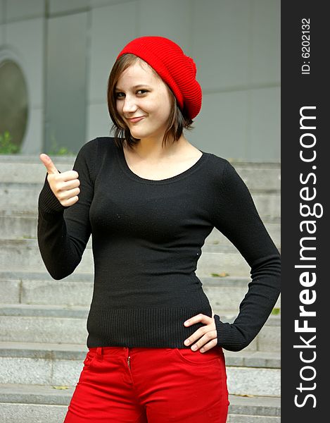A girls with red cap stretches thumb in the air