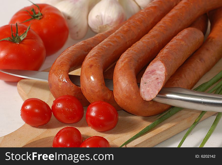 Delicious sausage and tomatoes on the chopping board