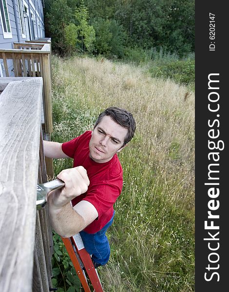 Frustrated man standing on a ladder fixing a porch with a wrench. Vertically framed photo. Frustrated man standing on a ladder fixing a porch with a wrench. Vertically framed photo.