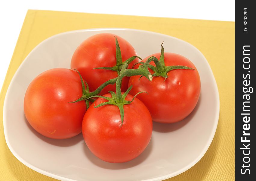 Bunch of tomato on white plate and place mat. Bunch of tomato on white plate and place mat