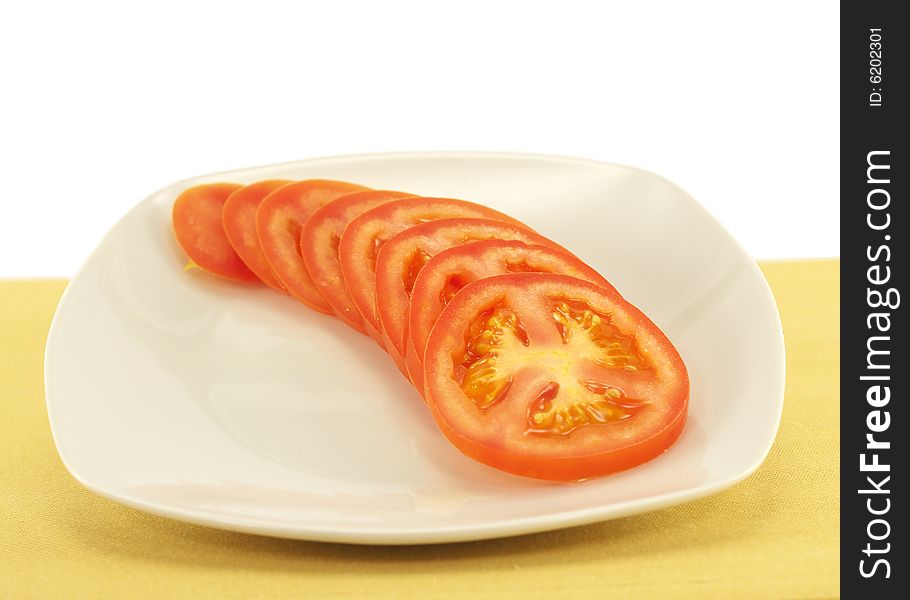 Tomato slices on white plate and yellow place mat. Tomato slices on white plate and yellow place mat