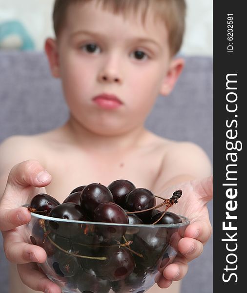 The boy holds a bowl with berries in hands