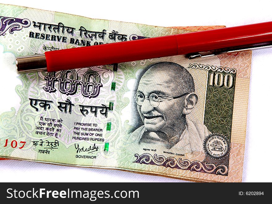 Hundred rupees note below a pen