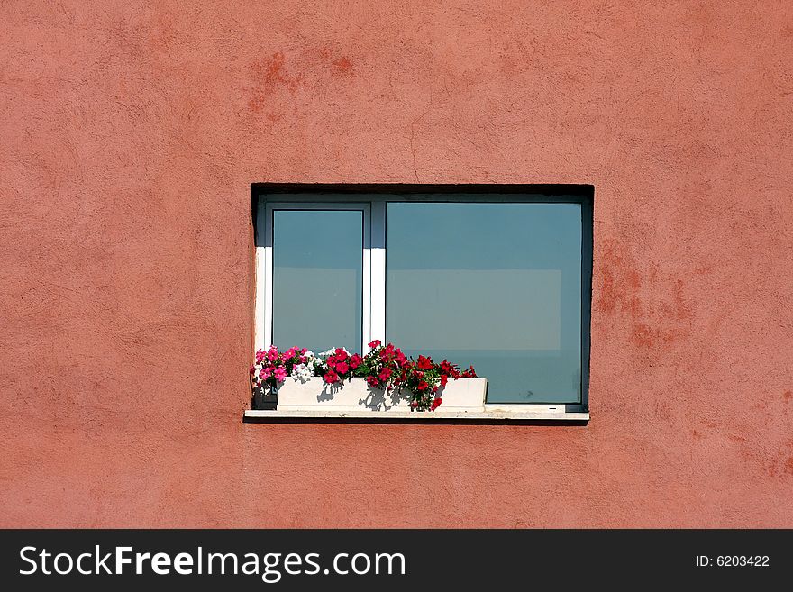 An Italian window is decorated with flowers in the summer. An Italian window is decorated with flowers in the summer.