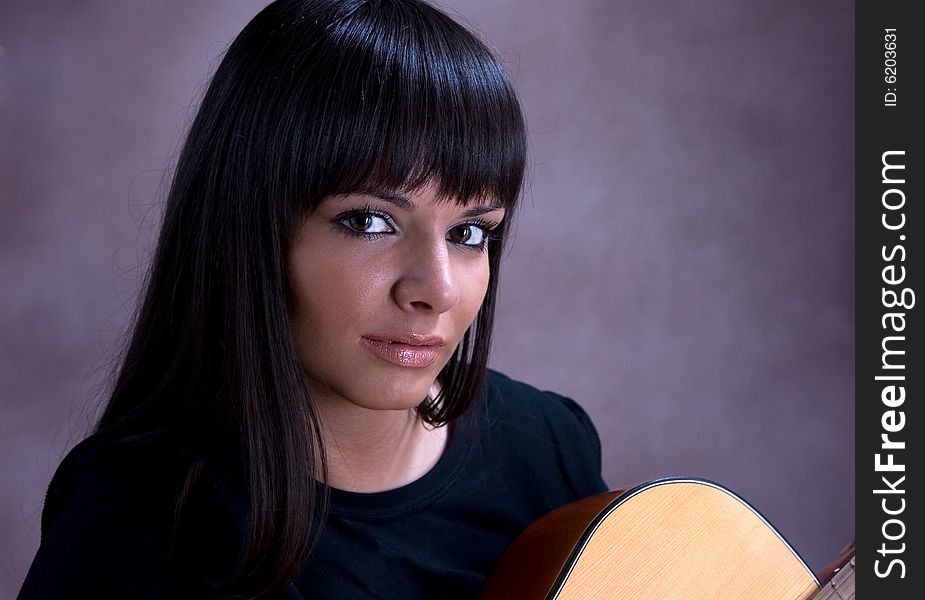 Portrait of beautiful young brunette playing guitar