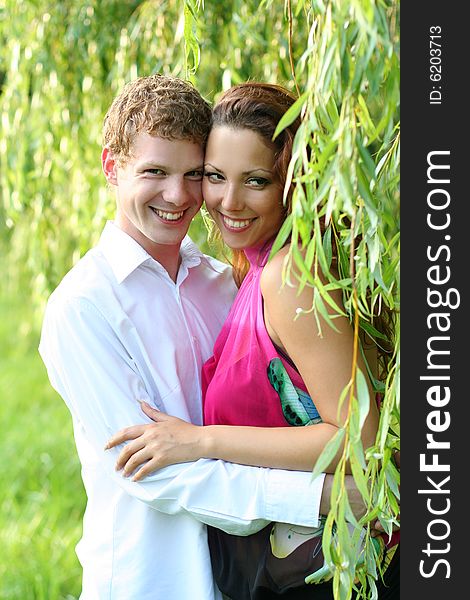 Cute young couple under green willow. Cute young couple under green willow