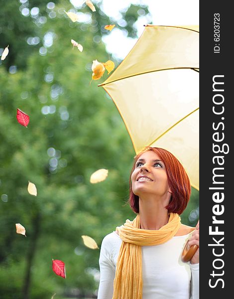 Beautiful young girl under yellow umbrella in the autumn park. Beautiful young girl under yellow umbrella in the autumn park