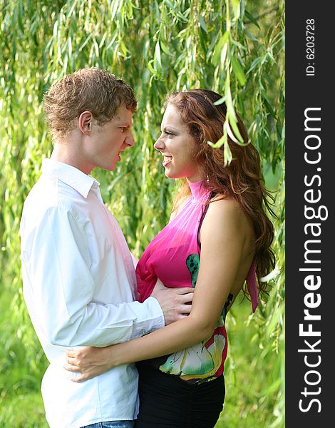 Funny young couple under green willow