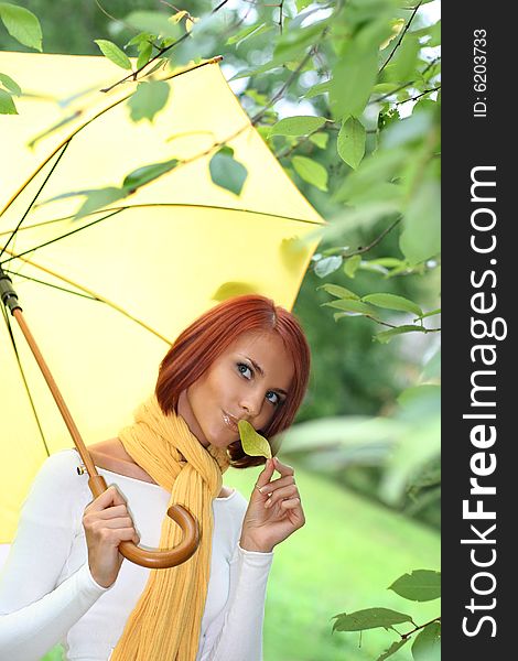 Beautiful young girl under yellow umbrella in the autumn park. Beautiful young girl under yellow umbrella in the autumn park