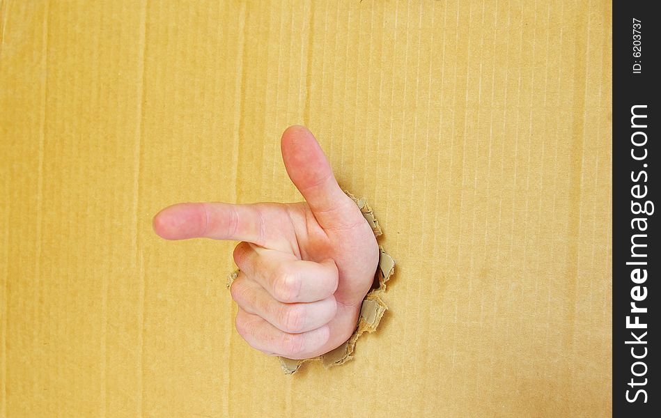 Hand pointing with index finger against a cardboard background