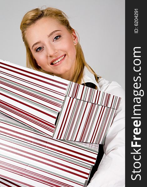 Smiling young woman holding a stack of boxes indoors. Smiling young woman holding a stack of boxes indoors