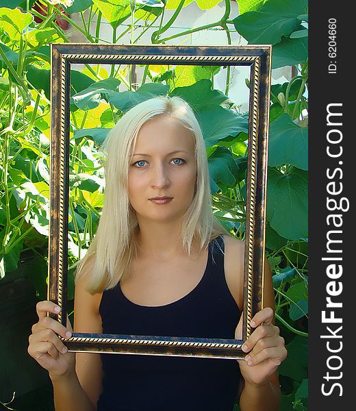 Young beautiful woman with frame in a summer garden. Young beautiful woman with frame in a summer garden.