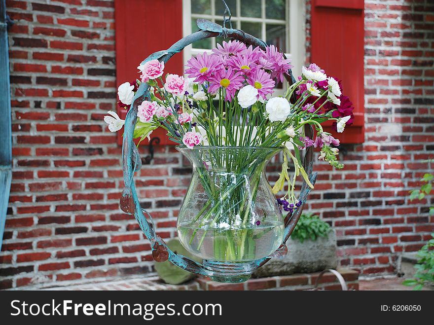 Hanging flowers with a brick house in the background.