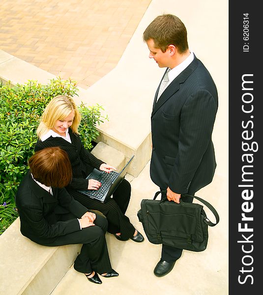 Business man and business woman listening to blond business woman talking about the project on her laptop. Business man and business woman listening to blond business woman talking about the project on her laptop