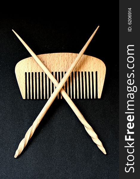 Wooden hairbrush and sticks for hair on a black background